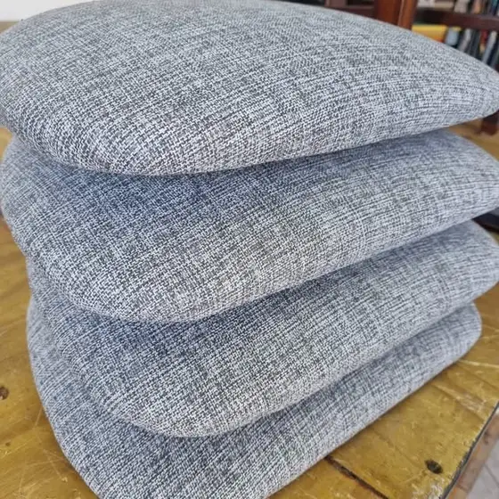 Almohadones de asiento en tela gris apilados sobre una mesa de madera