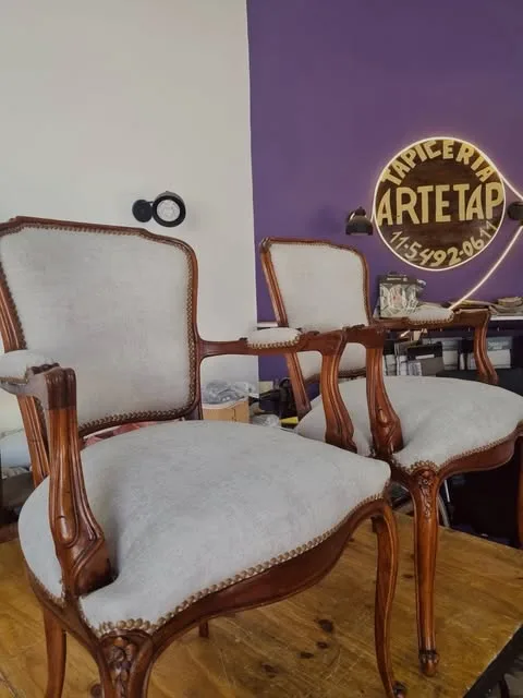 Sillones de estilo con estructura de madera tallada, tapizado claro y tachuelas