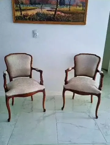 Dos sillones de madera con tapizado claro frente a un cuadro